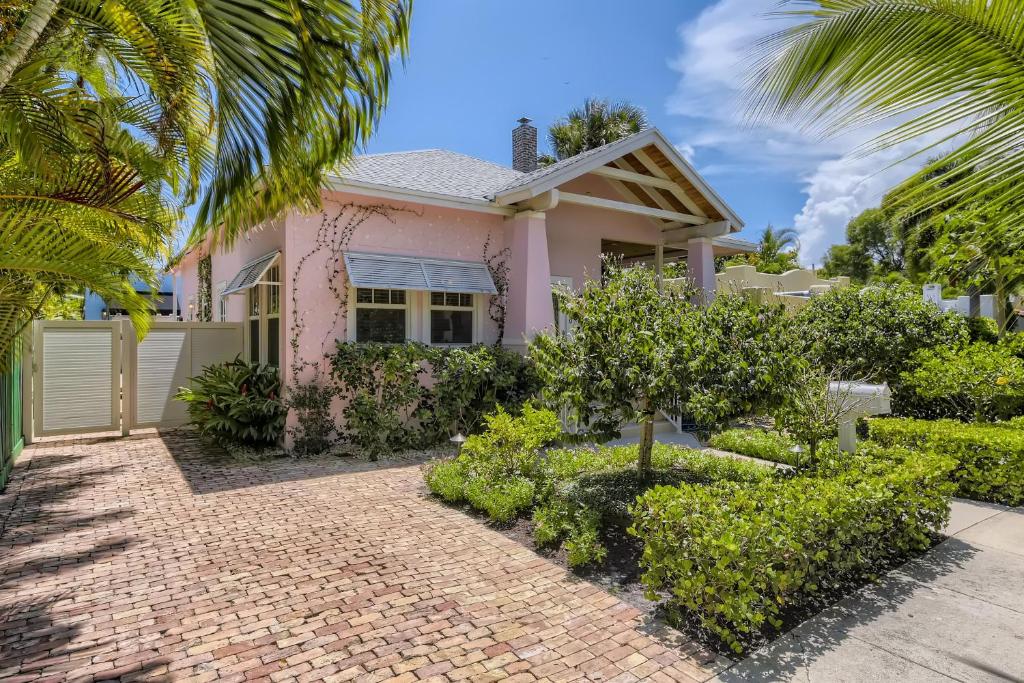 uma casa cor-de-rosa com árvores e arbustos à sua frente em Nini's Cottage 4bd 3ba Vacation Rental em West Palm Beach