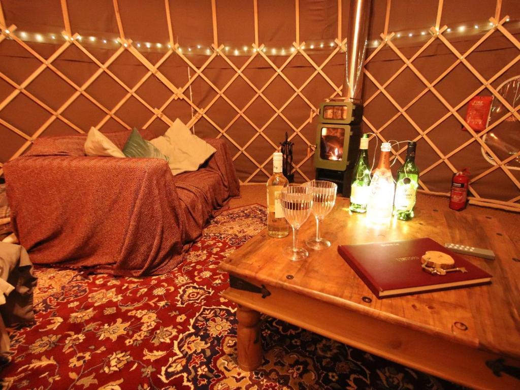 a room with a table with wine glasses and a bed at The Warren Yurt in Withyham