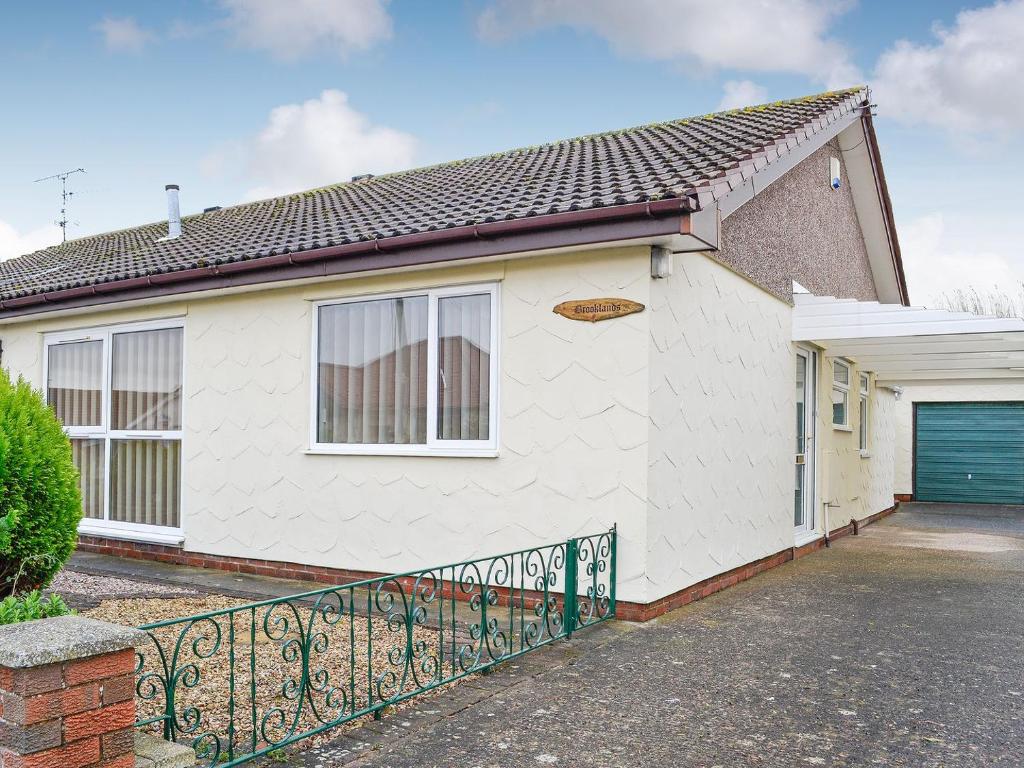 uma casa branca com um portão e uma garagem em Brooklands em Talacre