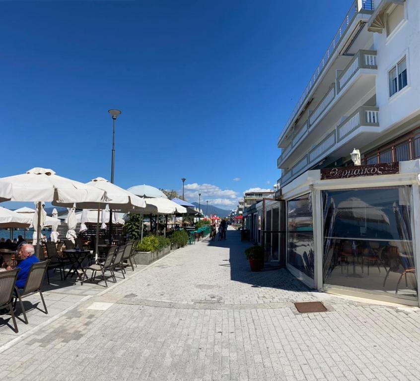 um passeio com mesas, cadeiras e guarda-sóis em Dellmar Apartment em Perea