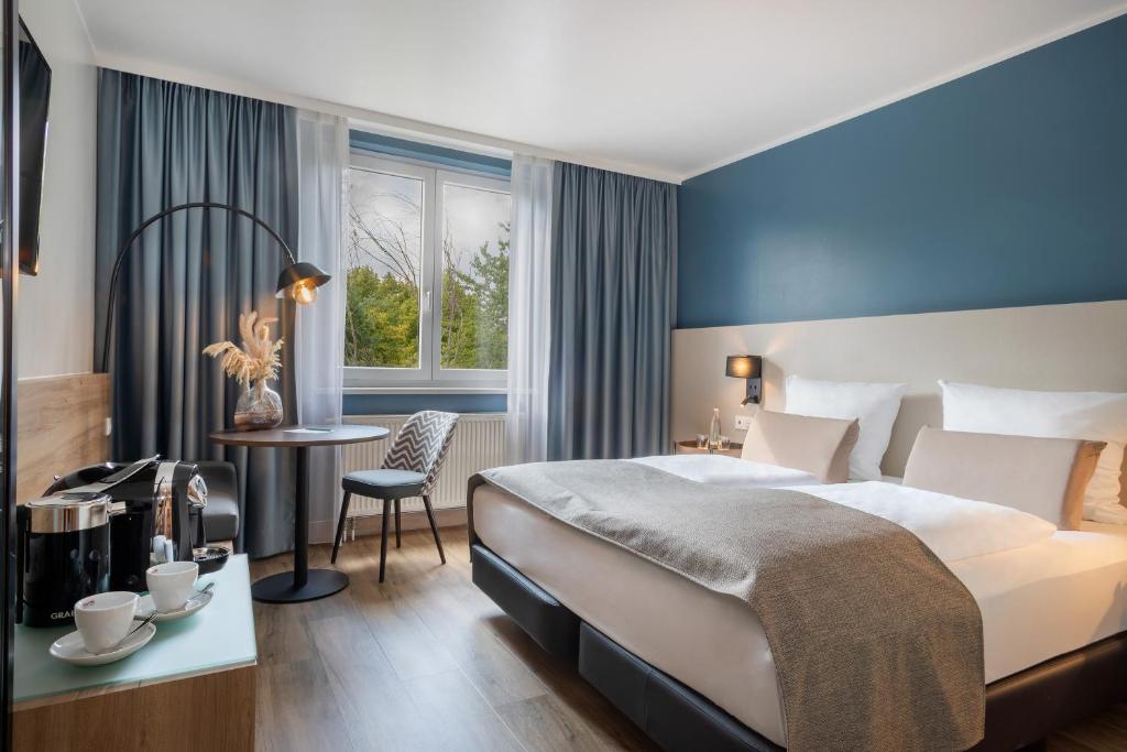 オーバーハウゼンにあるHotel Oberhausen Neue Mitte affiliated by Meliáのベッドとテーブルと椅子のあるホテルの部屋