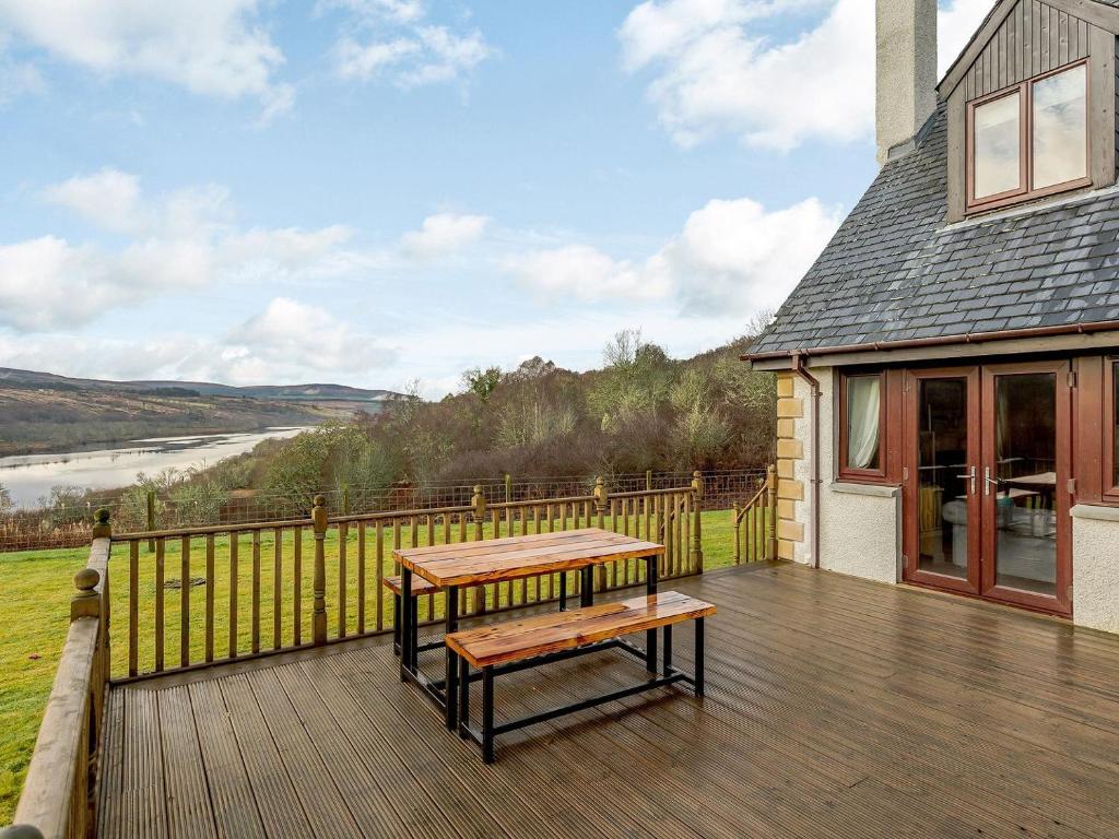 a wooden deck with a table and a bench on it at The Big Hoose in Achnahanat