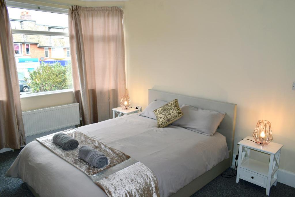 sypialnia z białym łóżkiem z dwoma stołami i oknem w obiekcie Beach escape 4 bedroom house, Sleeps 11, 2 free parking, garden, WIFI, Smart TV, newly decorated w Bournemouth