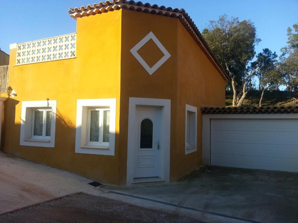 ein orangefarbenes Haus mit einer weißen Tür und einer Garage in der Unterkunft Un petit coin de paradis in Taradeau