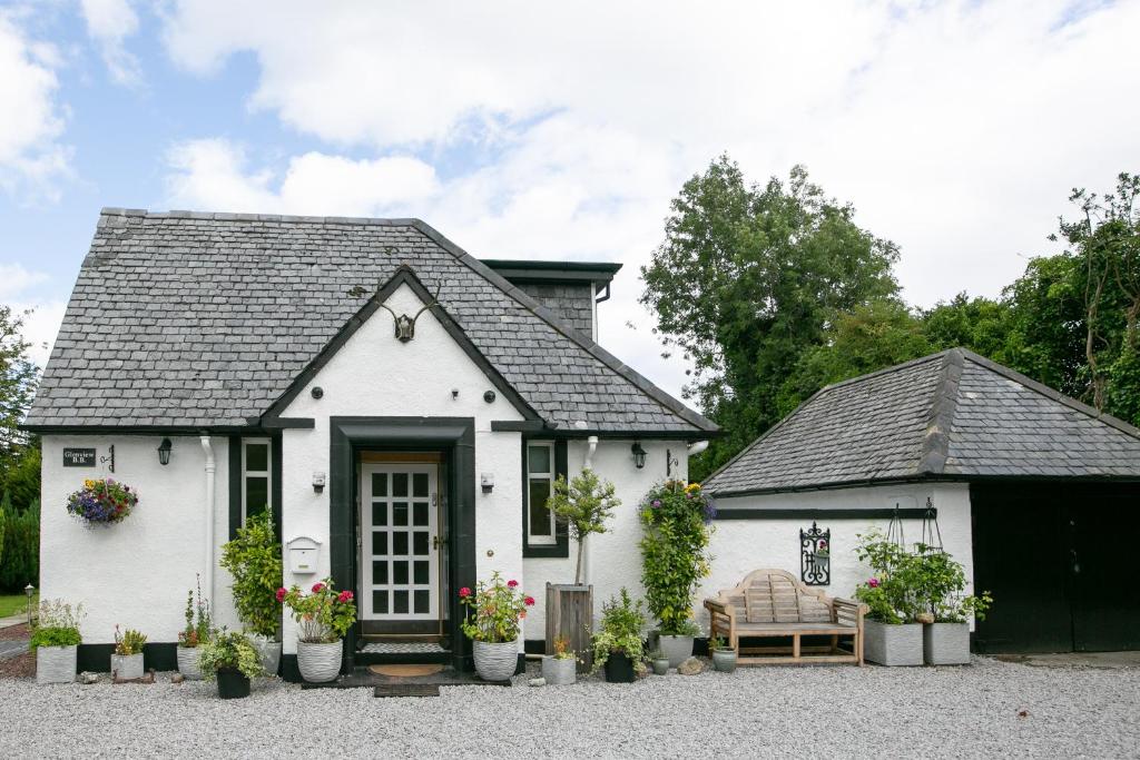 a white cottage with a black roof at Luss Cottages at Glenview in Luss