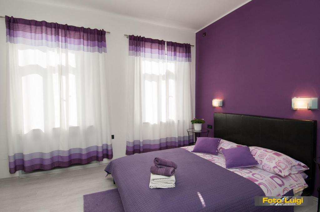 1 dormitorio púrpura con 1 cama con 2 toallas en Apartments KOMEL I, en Opatija