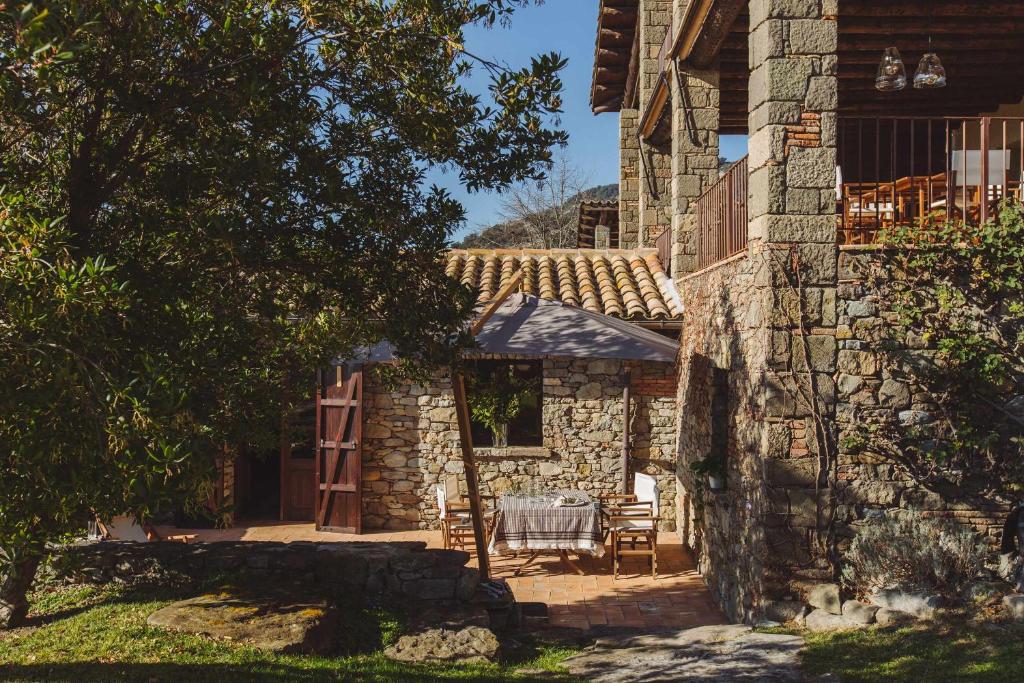a stone house with a table and chairs in a yard at La masovería de Mas Redortra in Sant Pere de Torelló