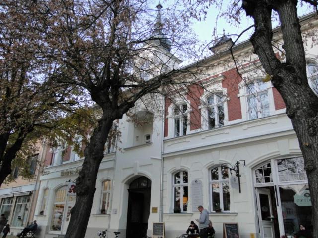 a man is sitting in front of a white building at Fewo Jüterbog City in Jüterbog