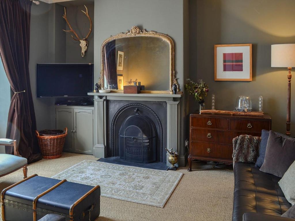 a living room with a fireplace and a mirror at Blackbird House in Alnwick