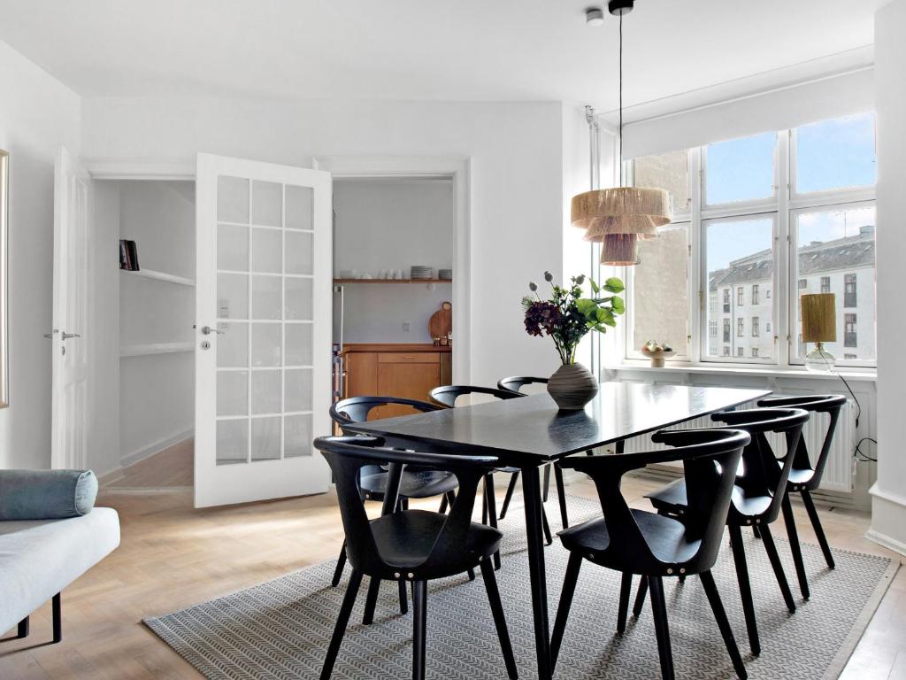 una cucina e una sala da pranzo con tavolo e sedie neri di Sanders Stage - Endearing Three-bedroom Apartment Near Nyhavn a Copenaghen