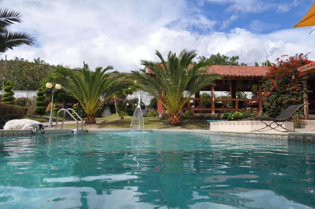einen Pool mit einem Brunnen vor einem Haus in der Unterkunft Lujosa Quinta Vacacional Ibarra in Ibarra