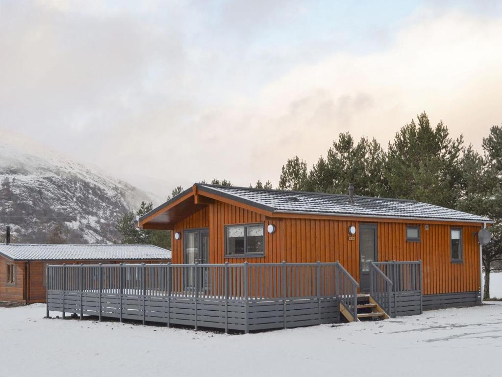 a log cabin in the snow with trees and mountains at The Den in Etteridge