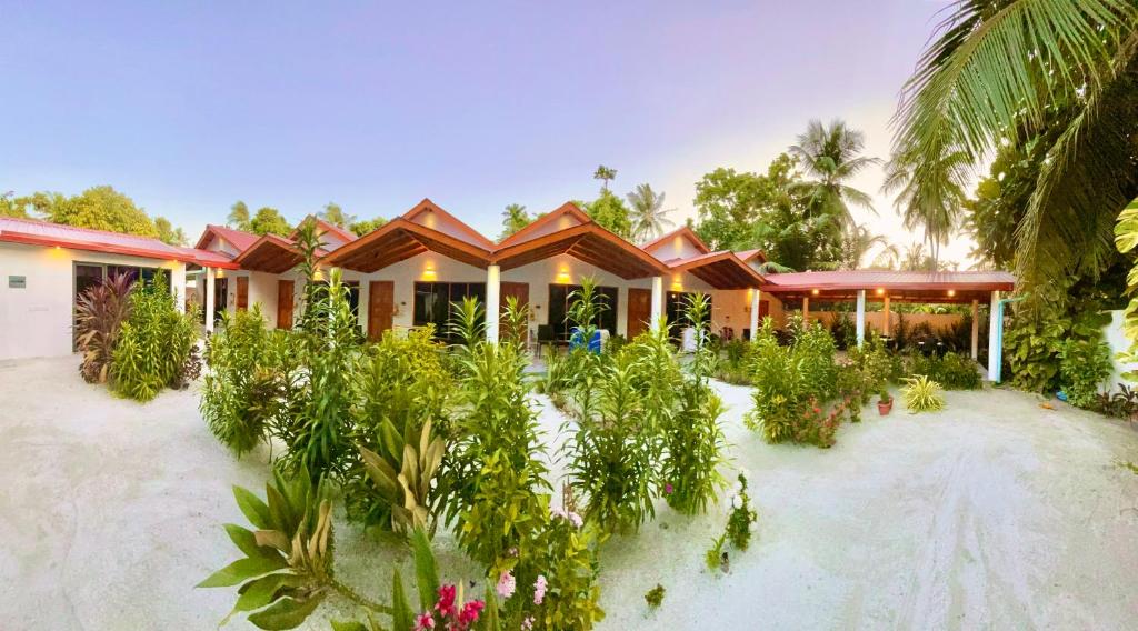 a house with a lot of plants in front of it at Thoddoo Beach Holiday Inn in Thoddoo