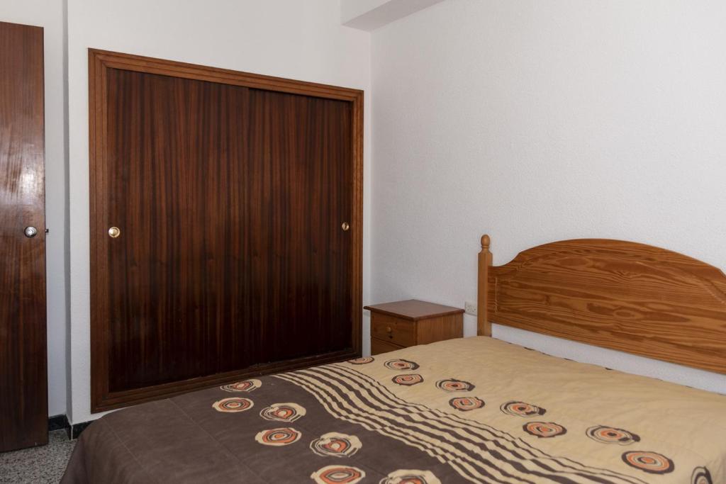 1 dormitorio con 1 cama y puerta de madera en Montemar, B-9º-26, en Cullera