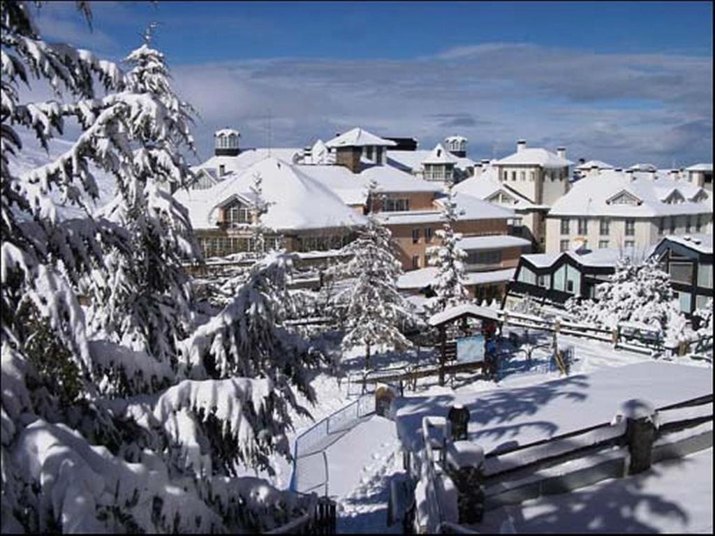 una ciudad cubierta de nieve con edificios en el fondo en Apartment Plaza de Pradollano, en Sierra Nevada