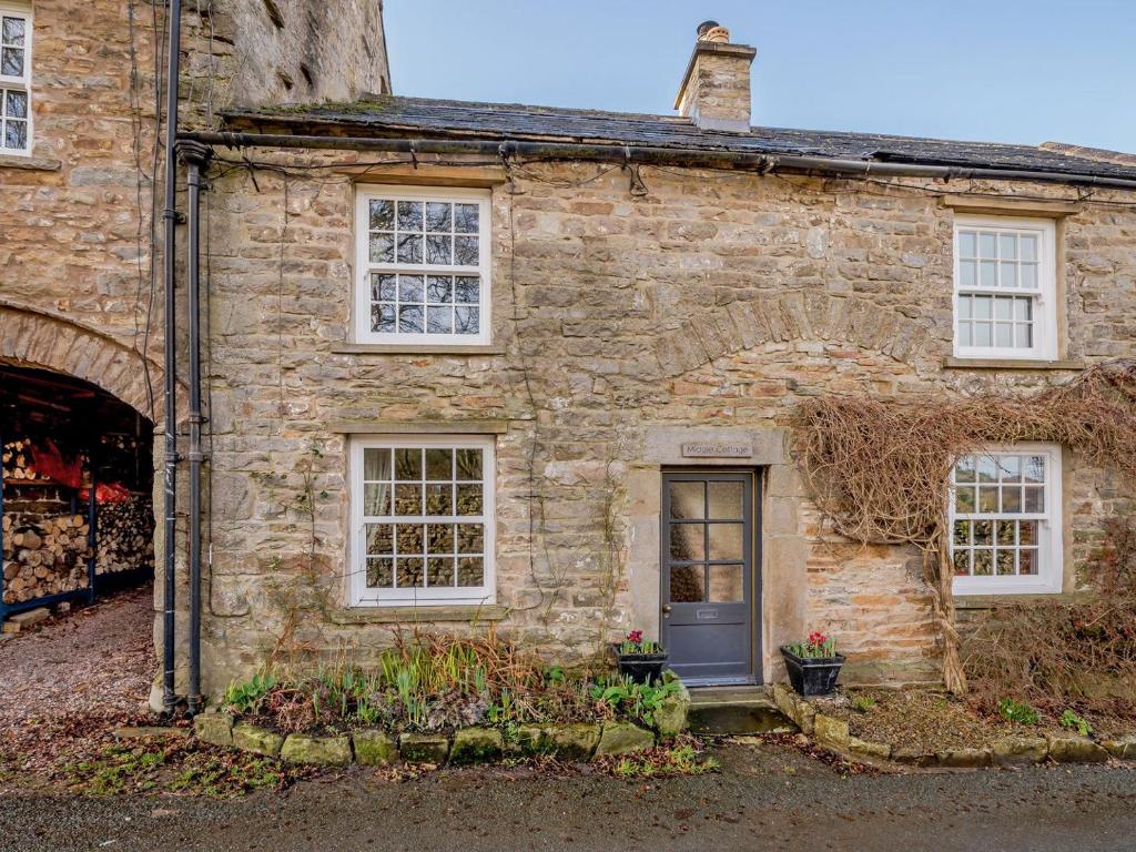 an old stone house with white windows and a door at Middle Cottage in West Burton