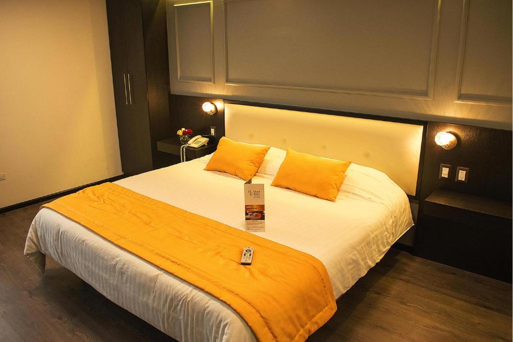 a bedroom with a large bed with an orange blanket at Hotel Italia in Cuenca