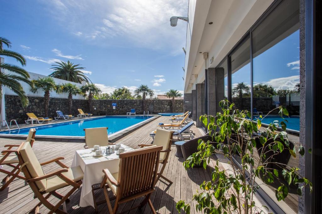 een patio met een tafel en stoelen naast een zwembad bij Antillia Hotel in Ponta Delgada