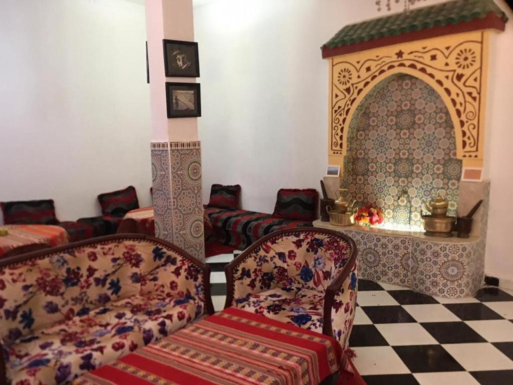 a living room with two chairs and a fireplace at Karim Sahara in Zagora