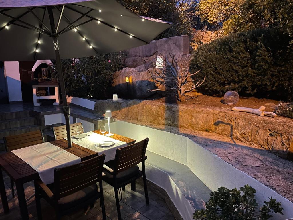 a table and chairs with an umbrella next to a river at Holiday Home Cesarica in Karlobag