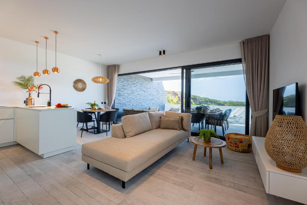 a living room and kitchen with a couch and a table at The Reef 28 Blue Bay Curacao in Dorp Sint Michiel