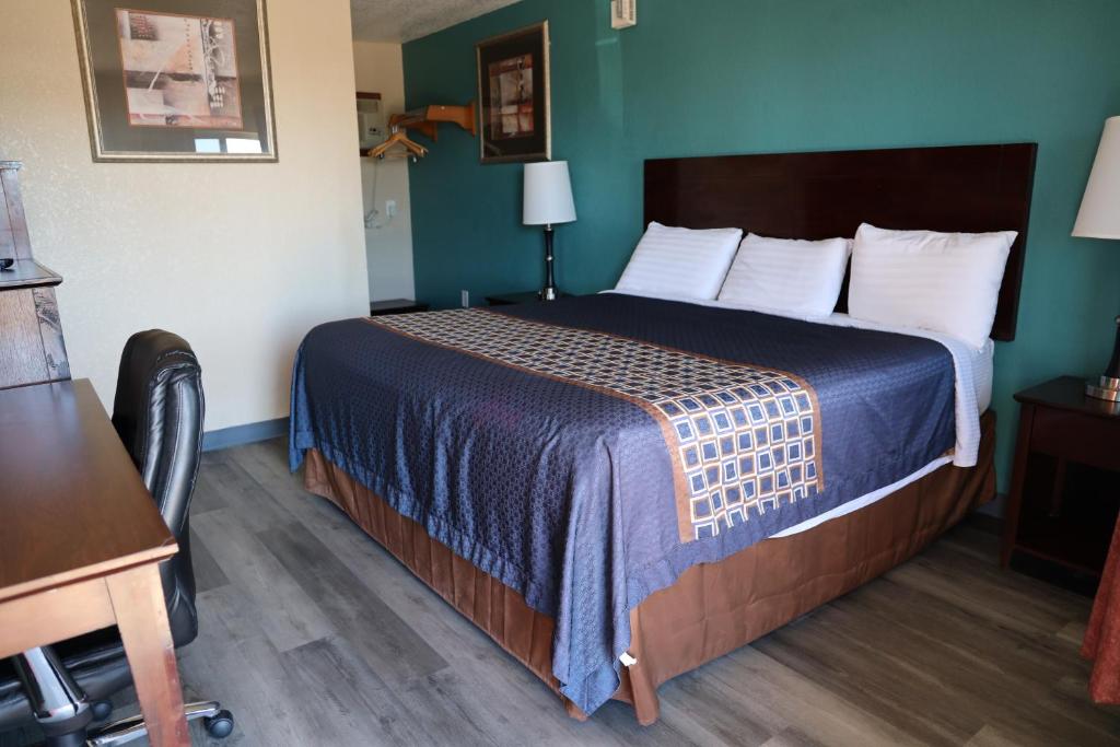 um quarto de hotel com uma cama com uma colcha azul em Budget Inn em Alamogordo