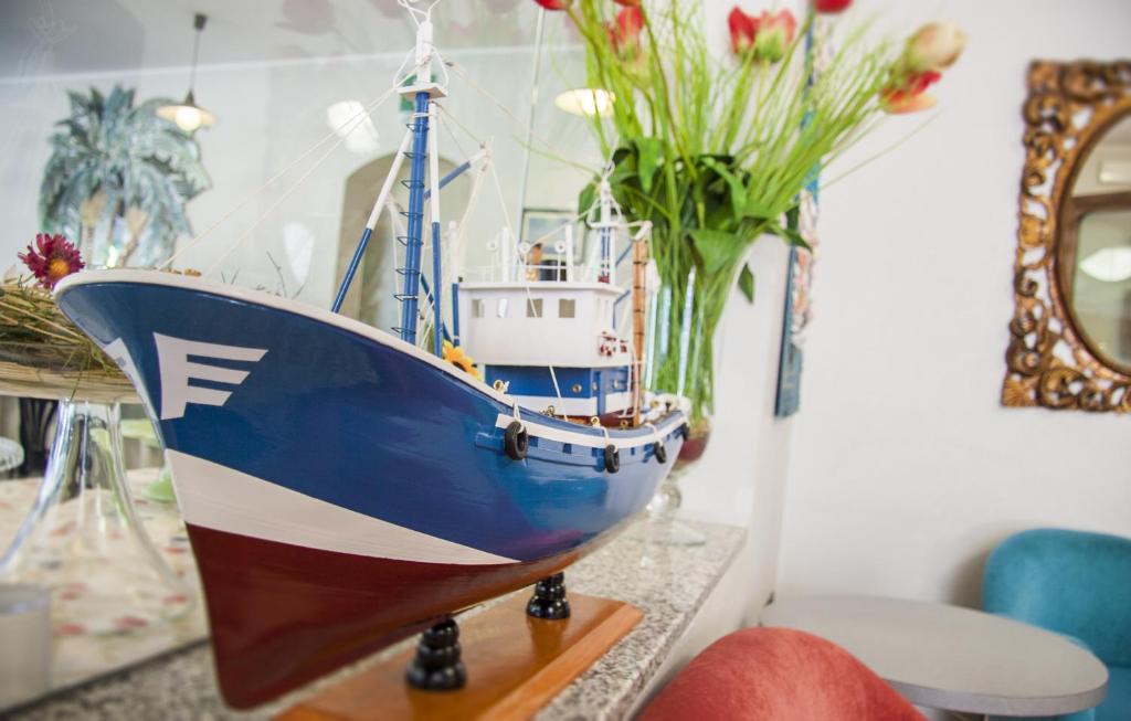 a model boat sitting on a table next to a vase of flowers at B&B Hotel Souvenir in Cesenatico