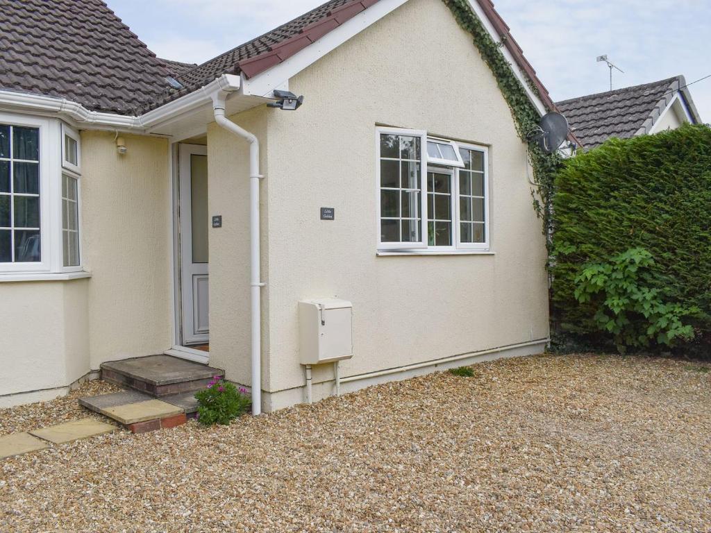 una casa blanca con una ventana y un seto en Little Gables, en Verwood