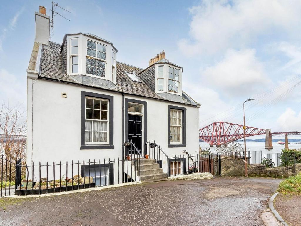 a white house with a fence and a bridge at Forth Reflections in Queensferry