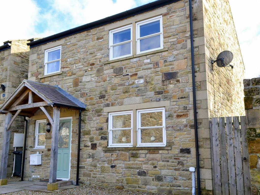 a brick house with a blue door and windows at Castle Holt in Otterburn