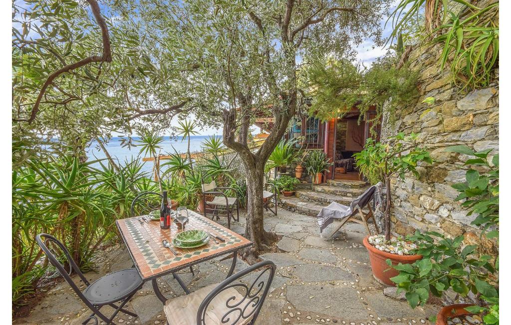 een tafel en stoelen in een tuin met een boom bij Awesome Home In Recco With House Sea View in Recco