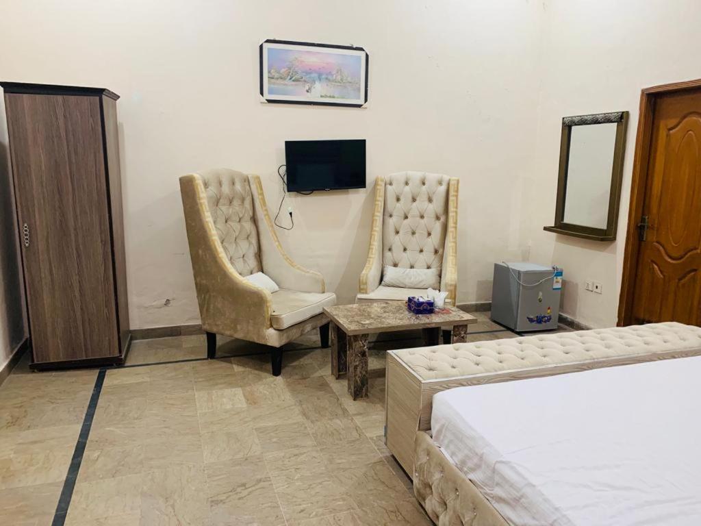 a bedroom with a bed and two chairs and a tv at Hotel Day IN One in Lahore