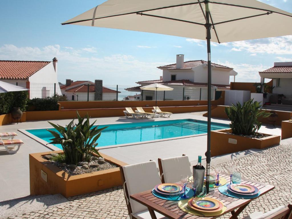 a patio with a table with an umbrella and a pool at Casa Azul in Praia da Areia Branca