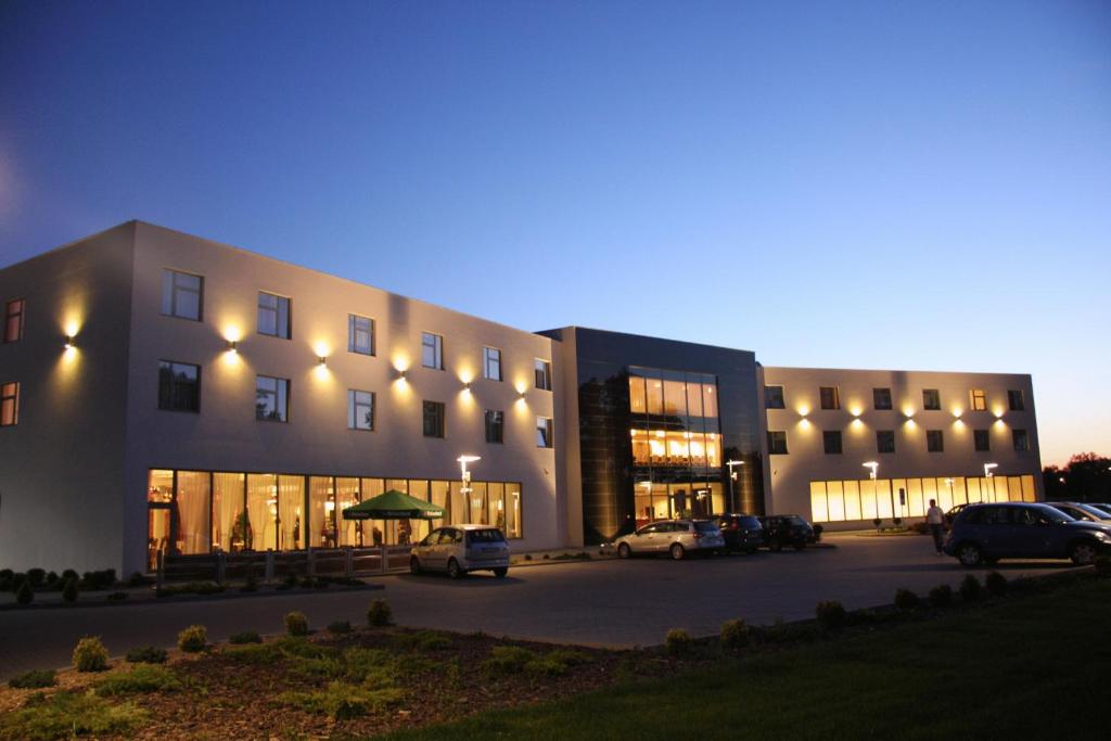 ein großes Gebäude mit Autos auf einem Parkplatz in der Unterkunft Hotel Hi-Fi Spa in Nowy Tomyśl