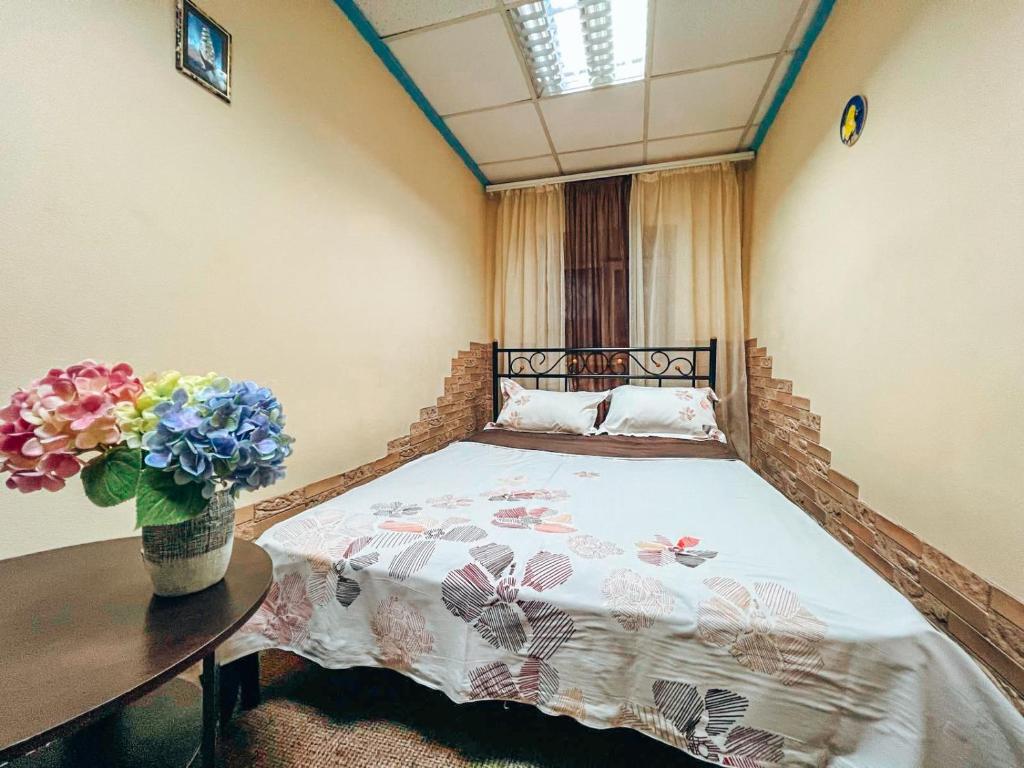 キーウにあるMini-hotel in the heart of Kievのベッドルーム1室(ベッド1台、花瓶付きのテーブル付)
