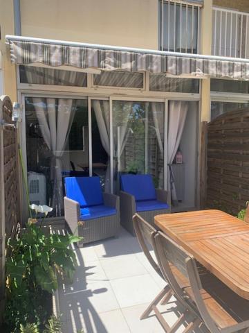 eine Terrasse mit blauen Stühlen und einem Holztisch in der Unterkunft PORTISSOL in Sanary-sur-Mer