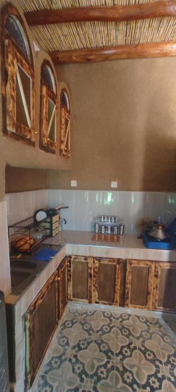 cocina con armarios de madera y suelo de baldosa en Casa Hamid, en Merzouga