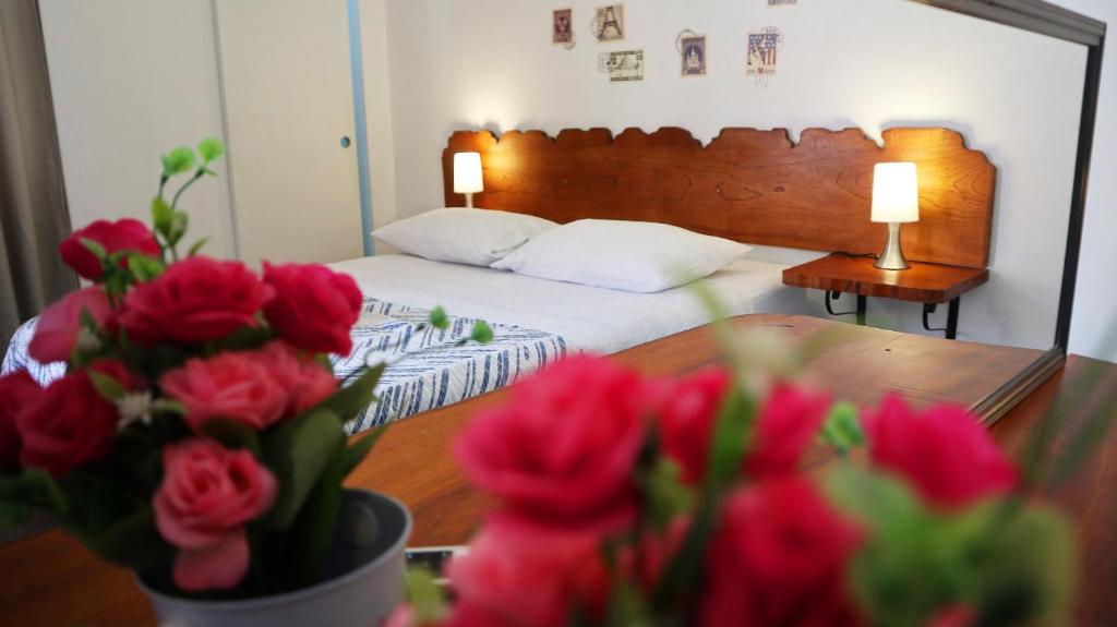 a bedroom with a bed and a table with red roses at Lunawasi Hospedaje in Lunahuaná