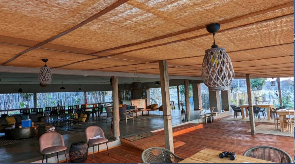 d'un salon avec des chaises, des tables et un plafond dans l'établissement Xhabe Safari Lodge Chobe, à Chobe