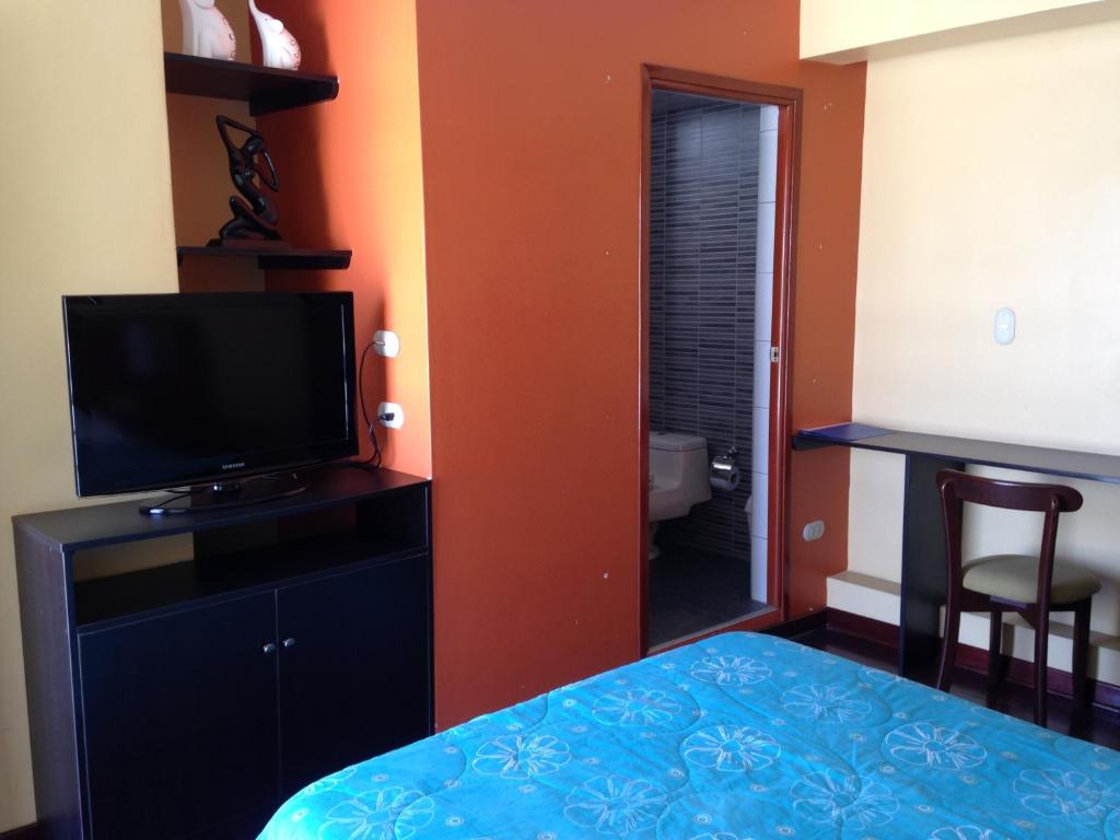 a room with a bed and a television and a bathroom at Hotel Los Cocos in Chimbote