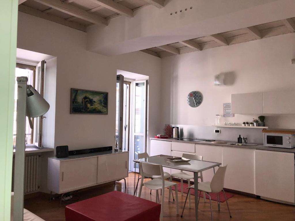 a kitchen with white cabinets and a table and chairs at Emma Home adiacente alla Piazza Ducale in Vigevano