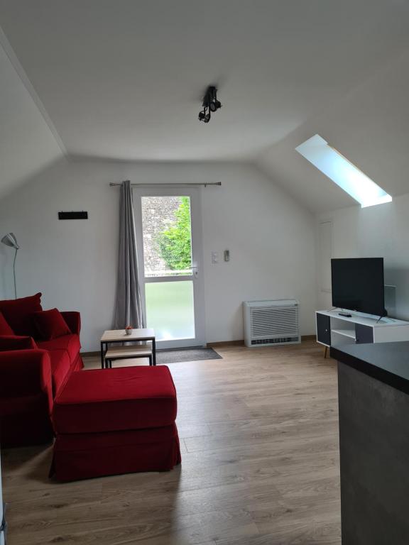 ein Wohnzimmer mit einem roten Sofa und einem TV in der Unterkunft Gîte de la Gourgeonne in Nervezain