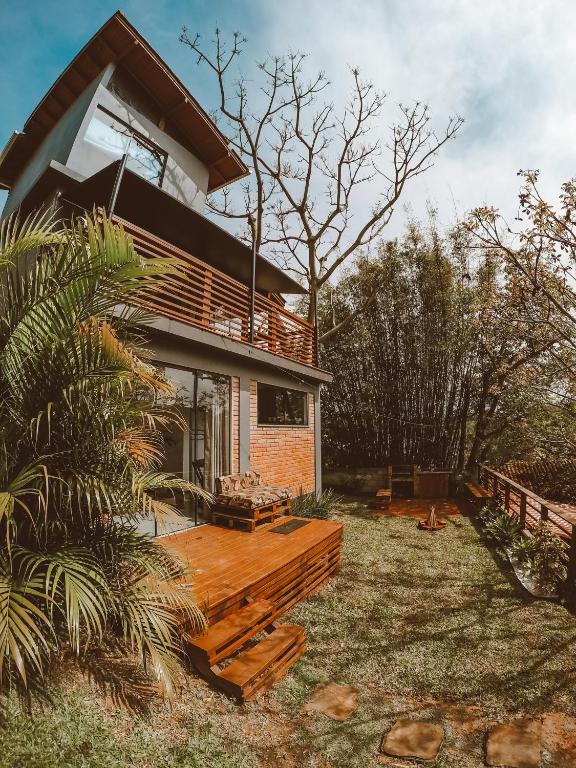 a house with a wooden deck in the yard at Pousada Refúgio do Vale - Praia do Rosa in Praia do Rosa