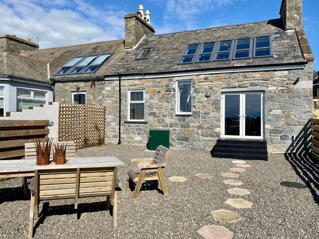 a stone house with a table and chairs in front of it at Saltlife Cottage in Port William