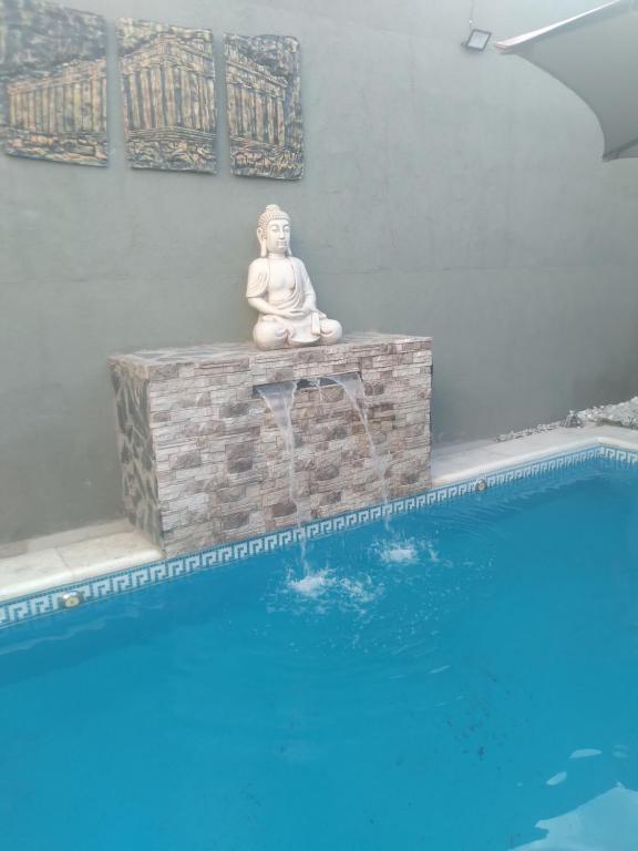 uma estátua de Buda sentada numa parede ao lado de uma piscina em Apart hotel protomy em Villa Luzuriaga