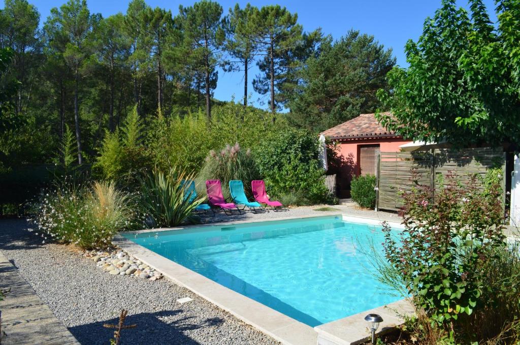 a swimming pool with lounge chairs next to a garden at Gîte Les Esparrus in Villecroze