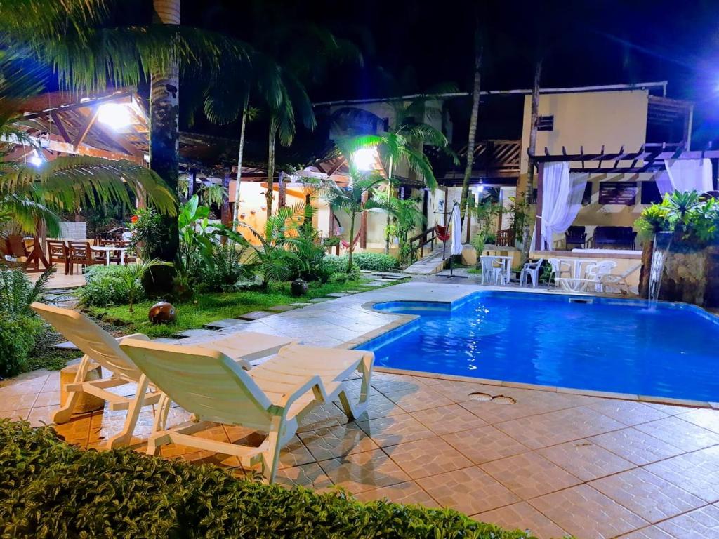 a swimming pool at night with two lounge chairs and a pool at Pousada Recanto dos Tangaras in Juquei