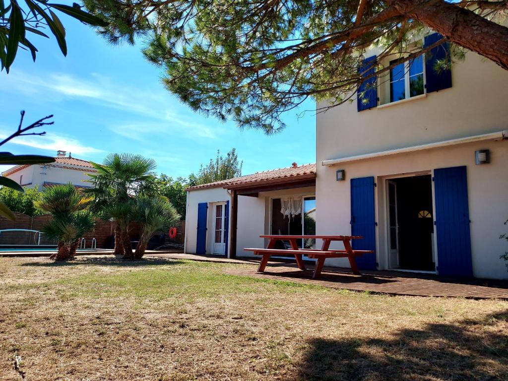 een huis met een picknicktafel ervoor bij Maison familiale avec piscine chauffée in Saint-Georges-de-Didonne