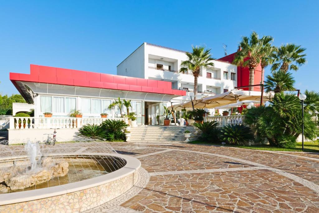 a building with a fountain in front of it at Hotel Mediterraneo in Porto Cesareo