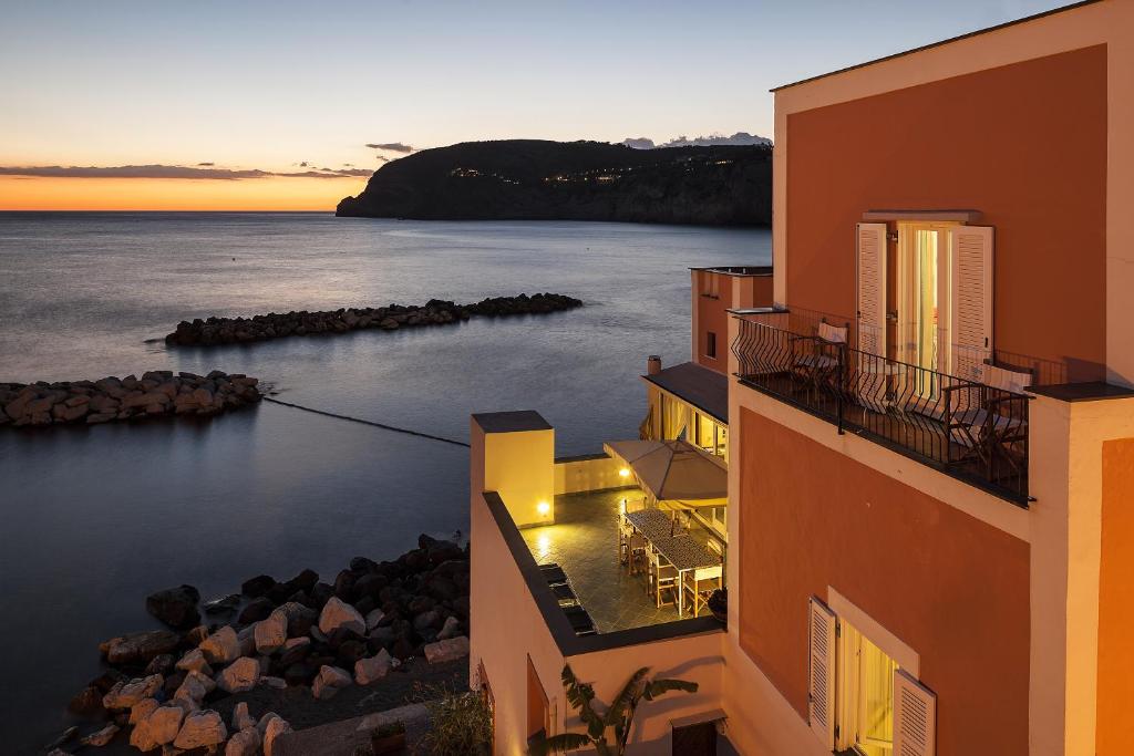 einen Blick auf das Meer zwischen den Gebäuden bei Sonnenuntergang in der Unterkunft Appartamenti Le Pleiadi - Sant'Angelo D'Ischia in Ischia